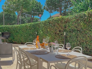 An outdoor dining area with a table set for four, surrounded by white chairs, and a stop sign in the background.