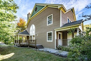 Une maison à deux étages avec un porche couvert, une cheminée et une pelouse bien entretenue.