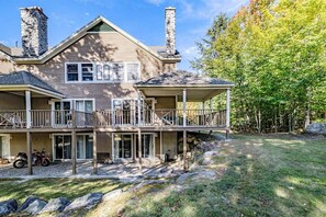 A two-story house with a balcony, stone chimneys, and a covered porch. - Powder Ridge Townhouse 33 (Newry)
