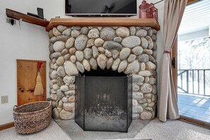 A stone fireplace with a screen, a wooden mantel, and a TV above it. - Powder Ridge Townhouse 33 (Newry)