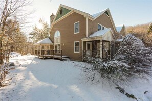 A two-story house with a covered porch, a snow-covered yard, and a clear sky. - Powder Ridge Townhouse 33 (Newry)