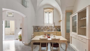 A dining area with a table set for four, a window above, and a kitchen in the background. - 3101 Casa di Paola by Barbarhouse (Lecce)