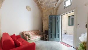 A cozy room with a red sofa, a patterned sofa, and a small table. There is a door leading to an outdoor area. - 3101 Casa di Paola by Barbarhouse (Lecce)