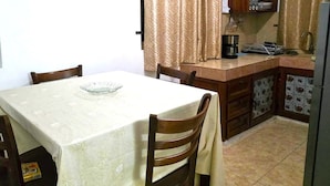 Ein Essbereich mit Tisch und Stühlen, eine Küche mit Kühlschrank und ein Schrank mit Geschirr.