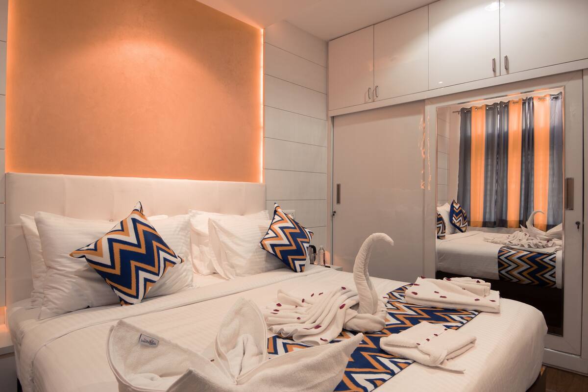 Habitación de hotel con una cama grande, dos almohadas, una bata y un espejo.