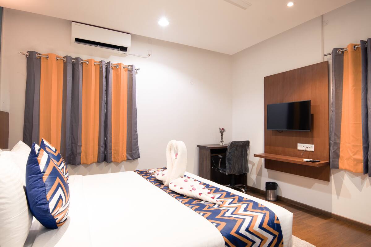 Una habitación de hotel moderna con cama, cortinas, televisor, escritorio y un cubo de basura.