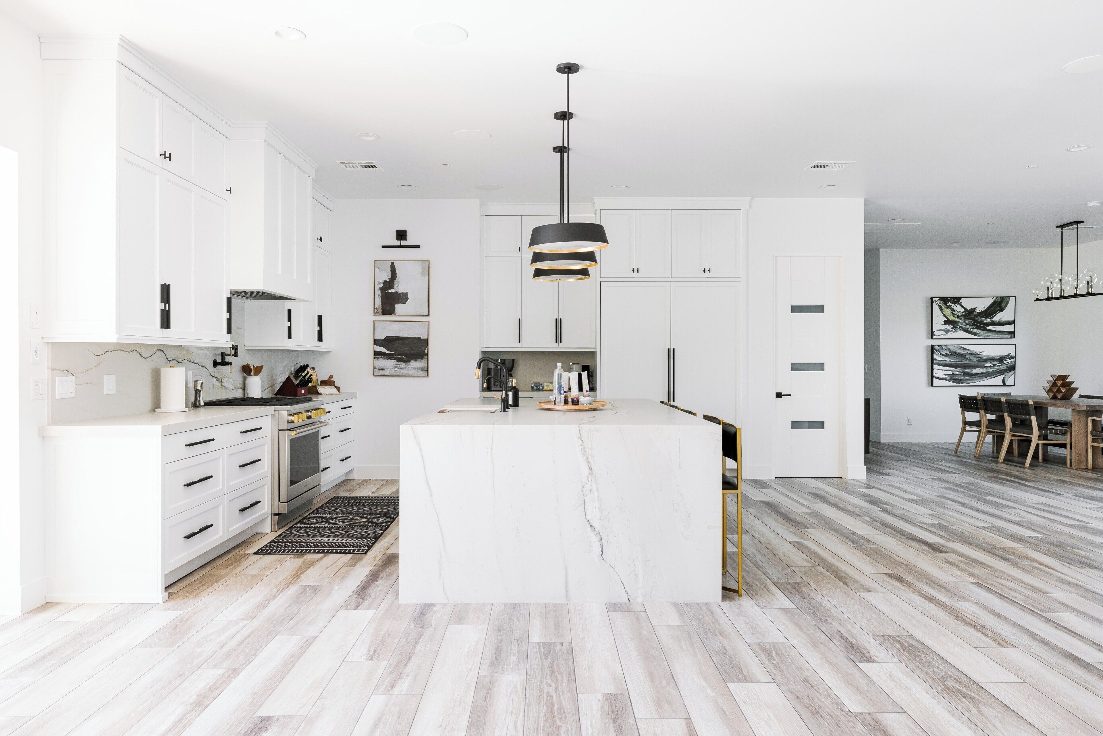A modern kitchen with white cabinetry, a central island, and a pendant light.