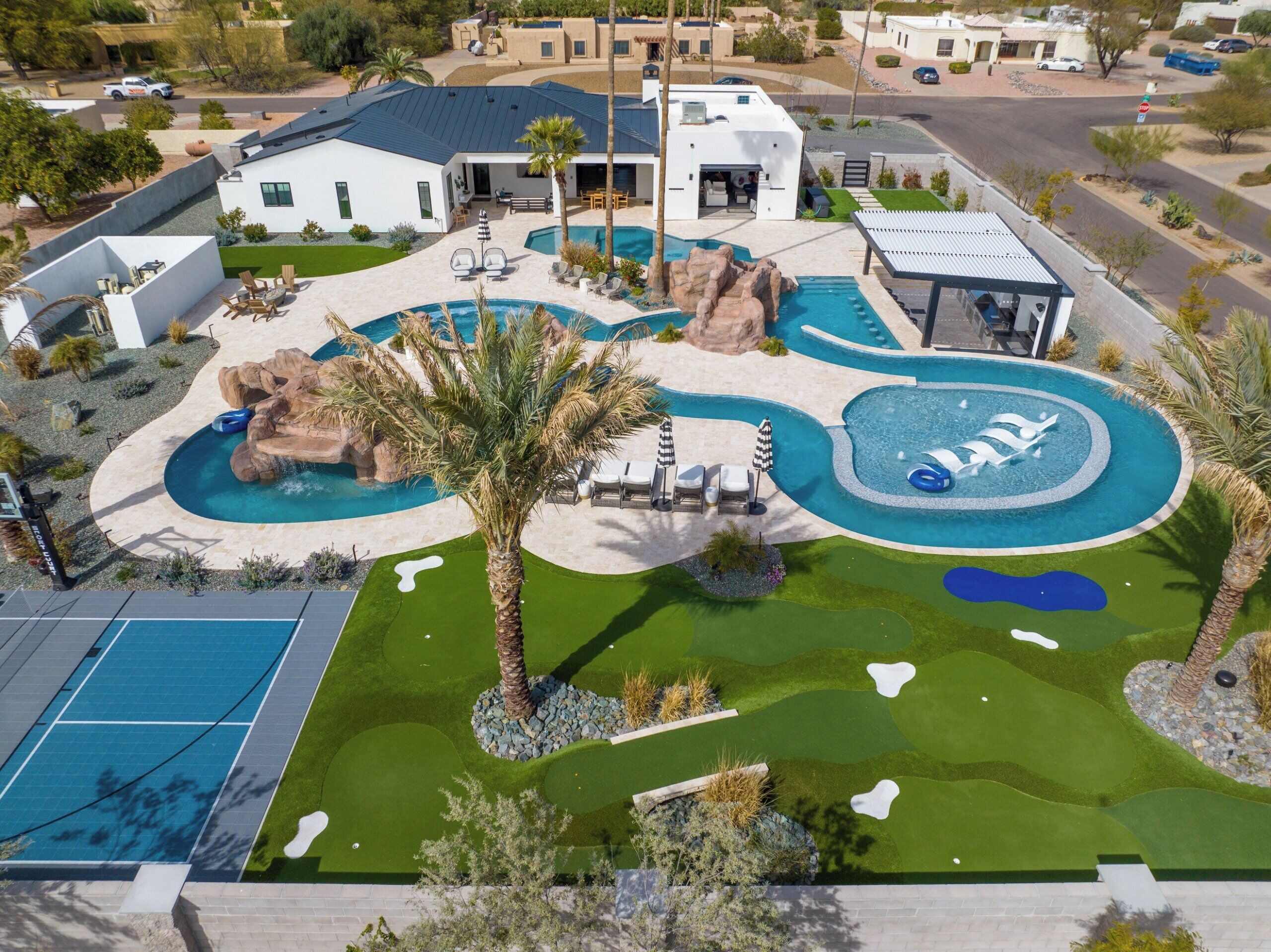 A modern residential property with a swimming pool, outdoor seating, and a well-maintained lawn.