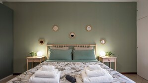A neatly made bed with floral bedding, two bedside tables with lamps, and a wall with decorative sunburst mirrors. - Camesena 40 | 2BR Apartment for 4 with Balcony near Tiburtina (Roma)