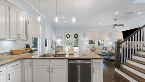 A spacious kitchen with granite countertops, white cabinetry, and a stainless steel dishwasher. - Bluebird Beach House - 3 Kings - Pet Friendly (Santa Rosa Beach)