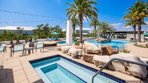 A pool area with lounge chairs, palm trees, and a small waterfall feature. - Bluebird Beach House - 3 Kings - Pet Friendly (Santa Rosa Beach)