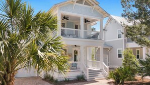 A two-story house with a balcony, a porch, and a staircase leading to the entrance. - Bluebird Beach House - 3 Kings - Pet Friendly (Santa Rosa Beach)