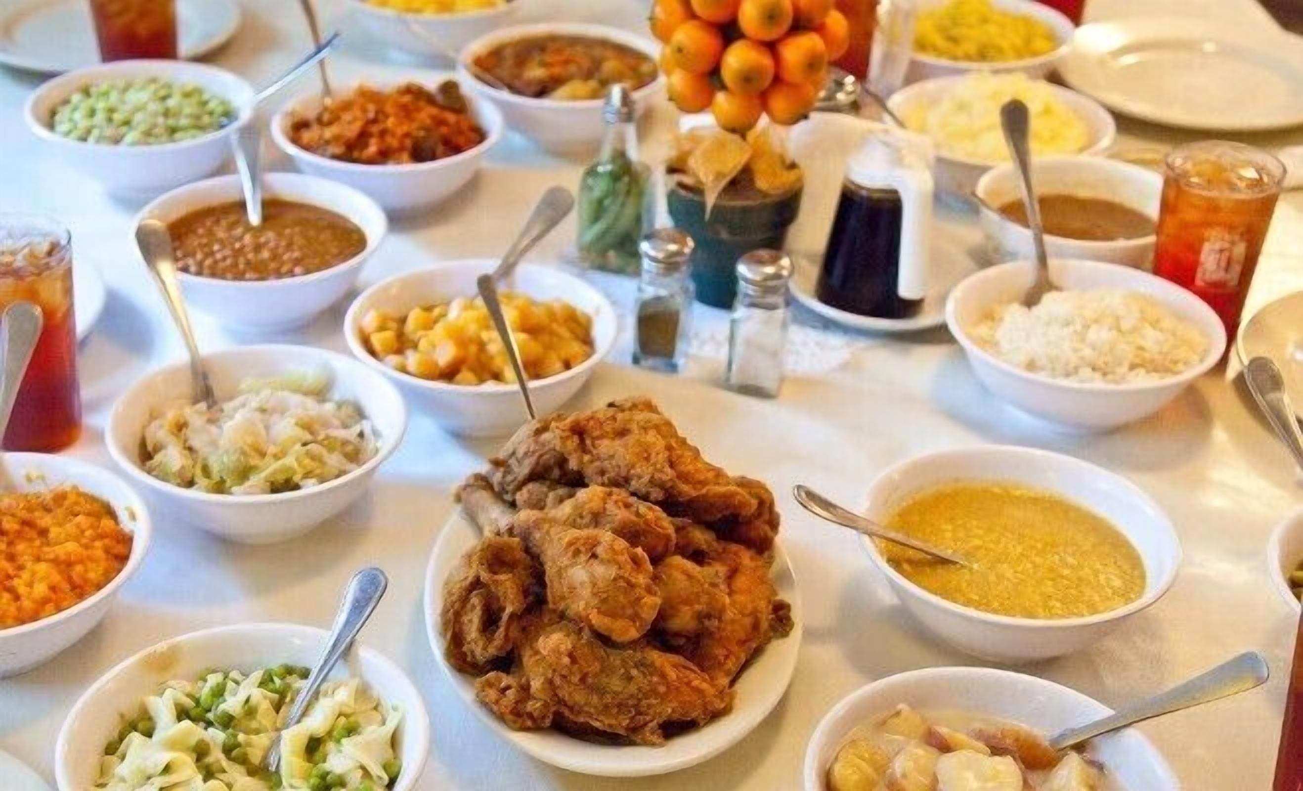 A table with various dishes and condiments, including fried chicken, rice, and multiple side dishes.
