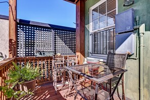 A wooden deck with a glass table and chairs, a potted fern, and a wooden fence. - Classic Jones Street Apartment-Off Street Parking Spot Included! (Savannah)