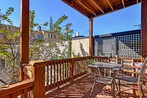 A wooden deck with a table and chairs, surrounded by a wooden railing and a lattice fence. - Classic Jones Street Apartment-Off Street Parking Spot Included! (Savannah)