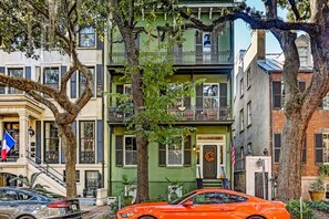 A multi-story building with a green facade, a balcony, and a car parked in front. - Classic Jones Street Apartment-Off Street Parking Spot Included! (Savannah)