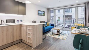 A modern apartment with a kitchen, dining area, and a balcony with a city view. - Once Upon a Tide - Apartment in the Heart of Poole (Poole)