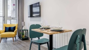 A dining area with a wooden table, green chairs, and a yellow armchair. - Once Upon a Tide - Apartment in the Heart of Poole (Poole)