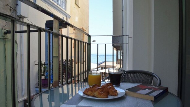 A balcony with a glass table, a plate of croissants, a glass of orange juice, and a book. - 2.1 NEW in center ROSES with WI-FI, AC and TV sat at 60 m MAR (Roses)