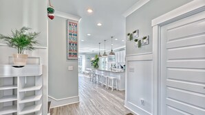 Une cuisine moderne avec des meubles blancs, un îlot central, des luminaires suspendus et une vue sur la salle à manger.