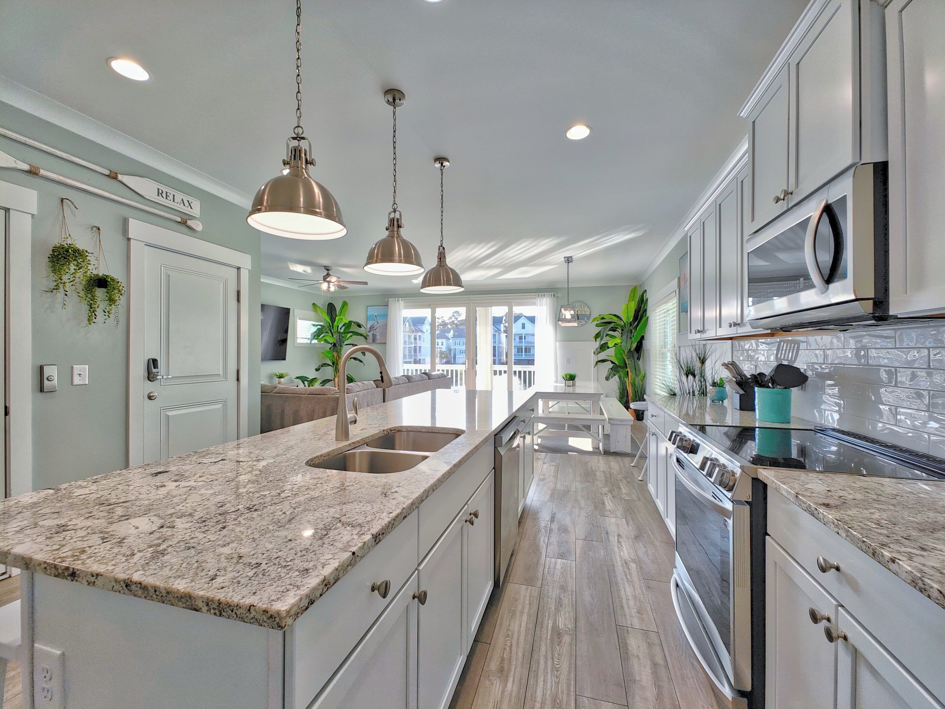 A modern kitchen with granite countertops, stainless steel appliances, and pendant lighting.