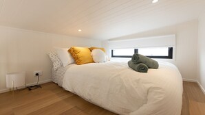 A bedroom with a large bed, a window, and a lamp. - Husky Tiny Home by Experience Jervis Bay (Huskisson)