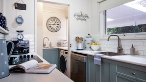 Una cocina moderna con lavadora, un lavamanos y un reloj en la pared.