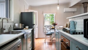 Una cocina moderna con armarios blancos, horno empotrado y ventana con vistas a zonas verdes.