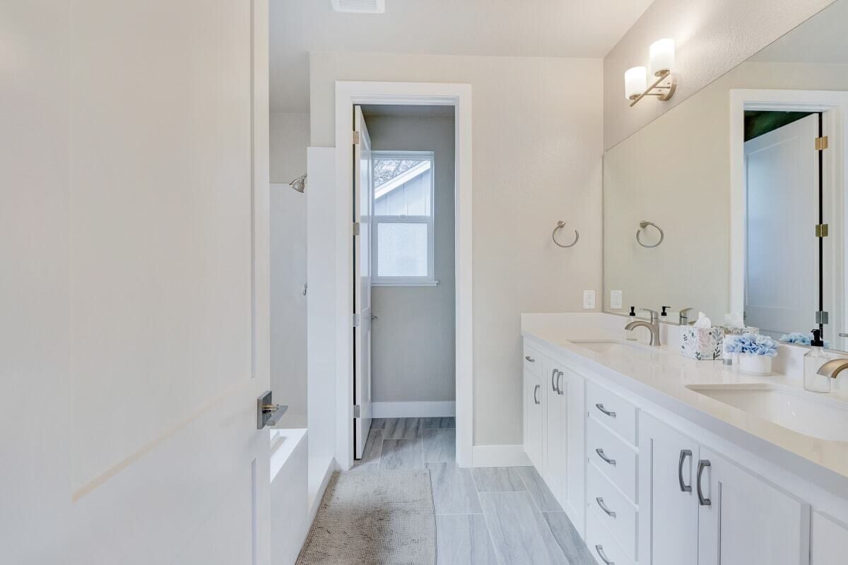 A modern bathroom with a double sink, a large mirror, and a walk-in shower.