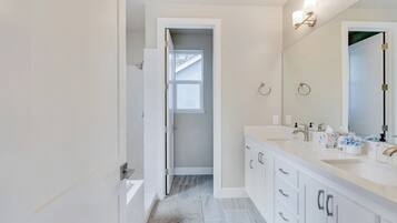 A modern bathroom with a double sink, a large mirror, and a walk-in shower.