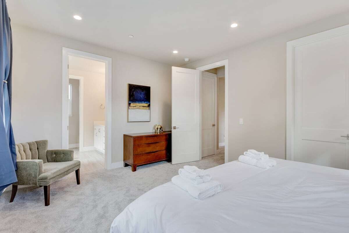 Une chambre avec un grand lit, une commode en bois et un tableau accroché au mur.