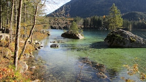 En klar bergssjö omgiven av träd och ett bergigt landskap.
