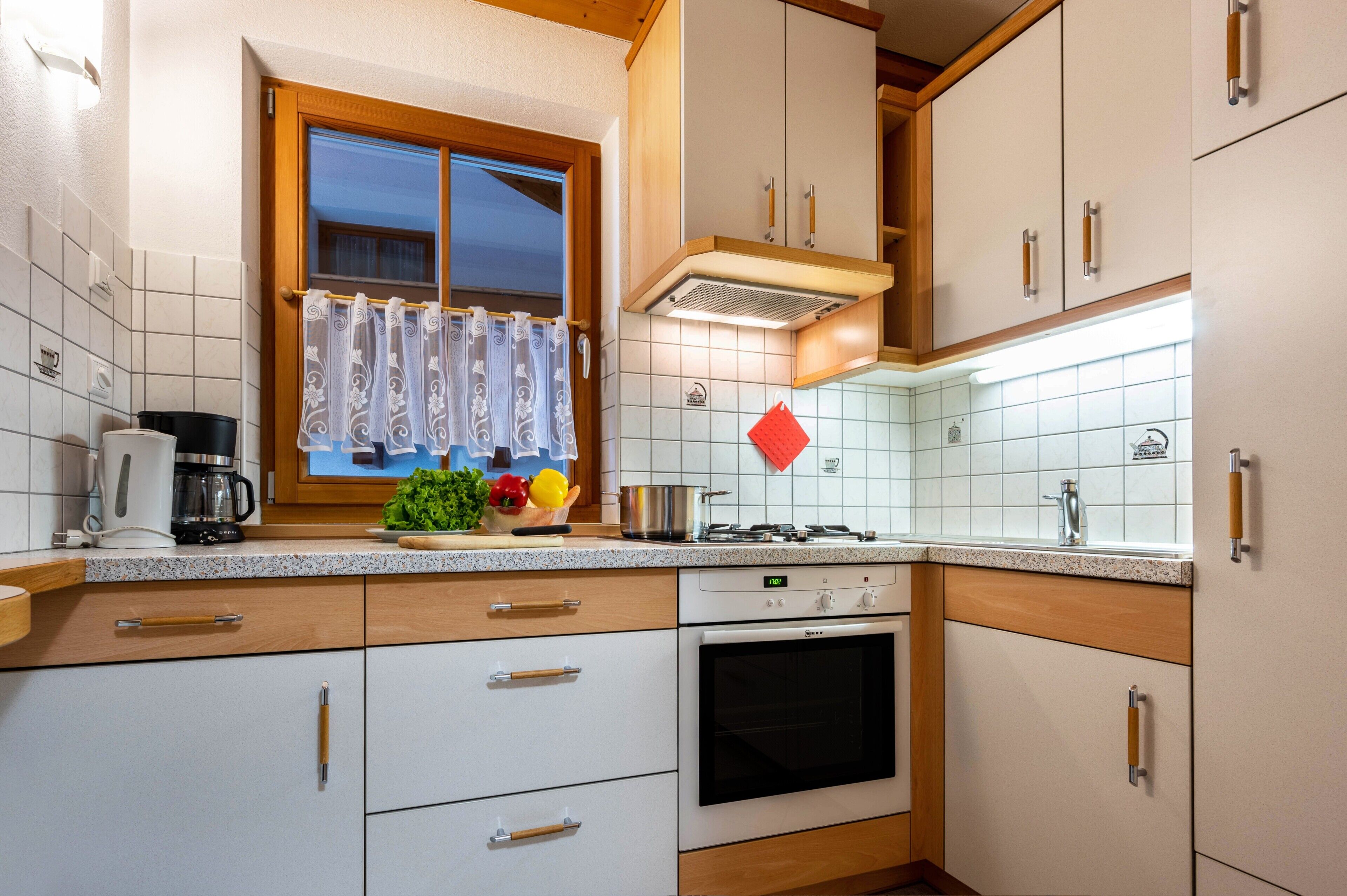 Une cuisine équipée d’une cuisinière, d’un four et d’une fenêtre avec des rideaux.