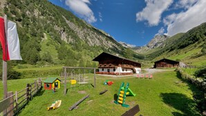 A mountain lodge with a playground, wooden cabins, and a clear view of the surrounding mountains.