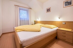 Une chambre à coucher avec un lit en bois, une table de chevet avec une lampe, une commode et un luminaire fixé au mur.