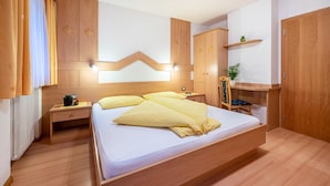 Una camera da letto con un letto, un'armadietto in legno, un comodino e una piccola scrivania con una sedia.