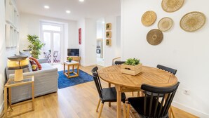 Ein modernes Wohnzimmer mit einem runden Holzes Esstisch, einem grauen Sofa und einem blauen Teppich.