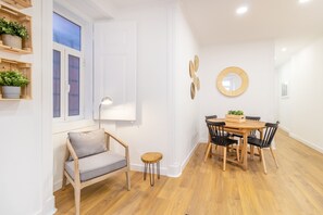 Un comedor moderno con una mesa de madera y sillas, una mesita redonda auxiliar y un banco con cojines.