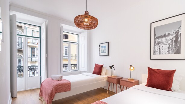 Ein Hotelzimmer mit Bett, Fensterbank, Nachttisch und einer Pendelleuchte.