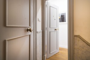 A hallway with a closed door, a light switch, and a framed picture on the wall. - Cozy Central Downtown II by Central Hill (Lisboa ciudad)