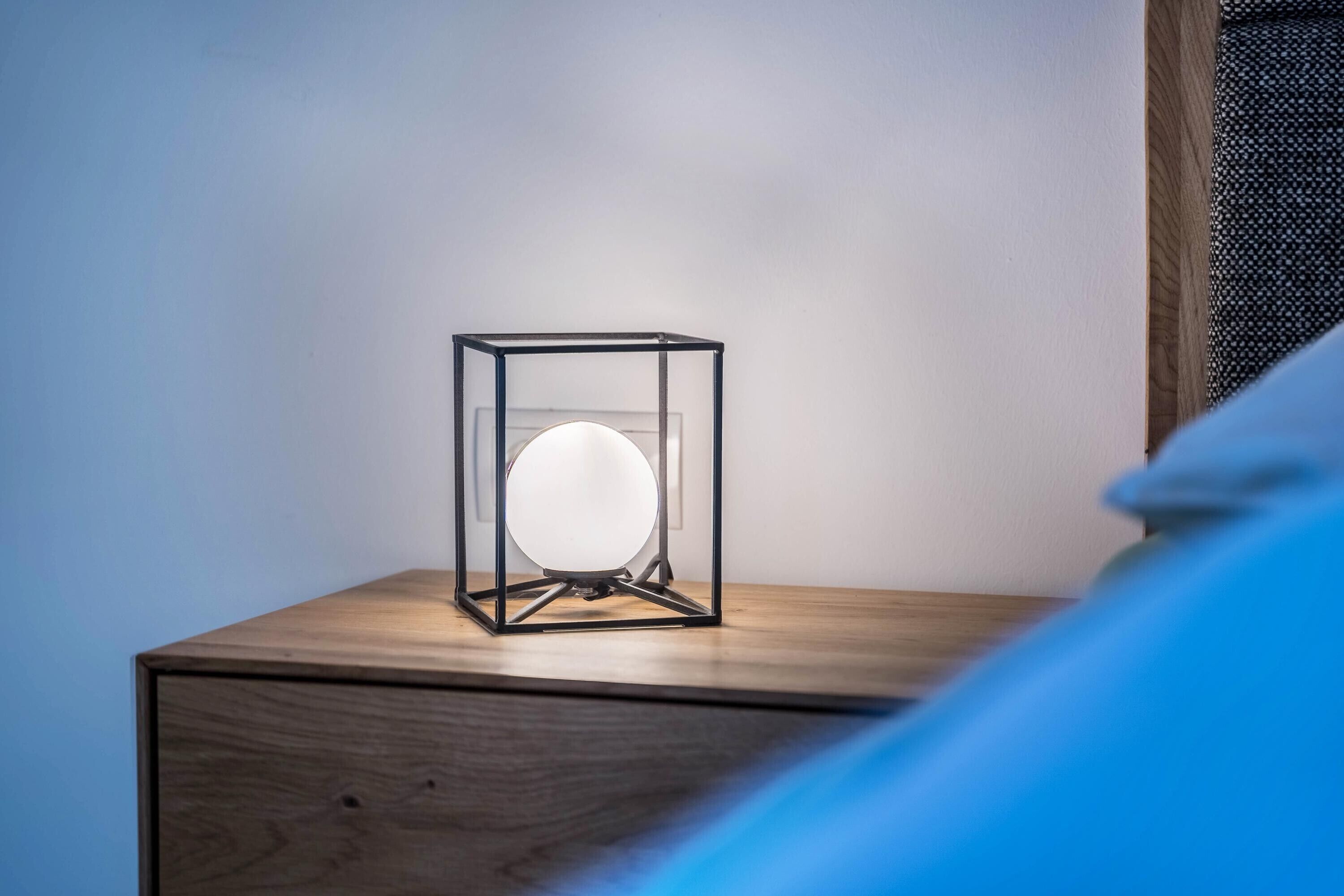 Ein Nachttisch mit einer modernen Lampe in einer transparenten Glaskonstruktion.