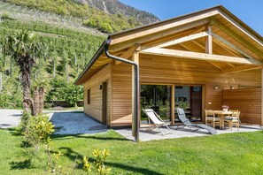 Une cabane en bois dotée d’un patio couvert, d’un espace recouvert de gravier et offrant une vue sur un vignoble.