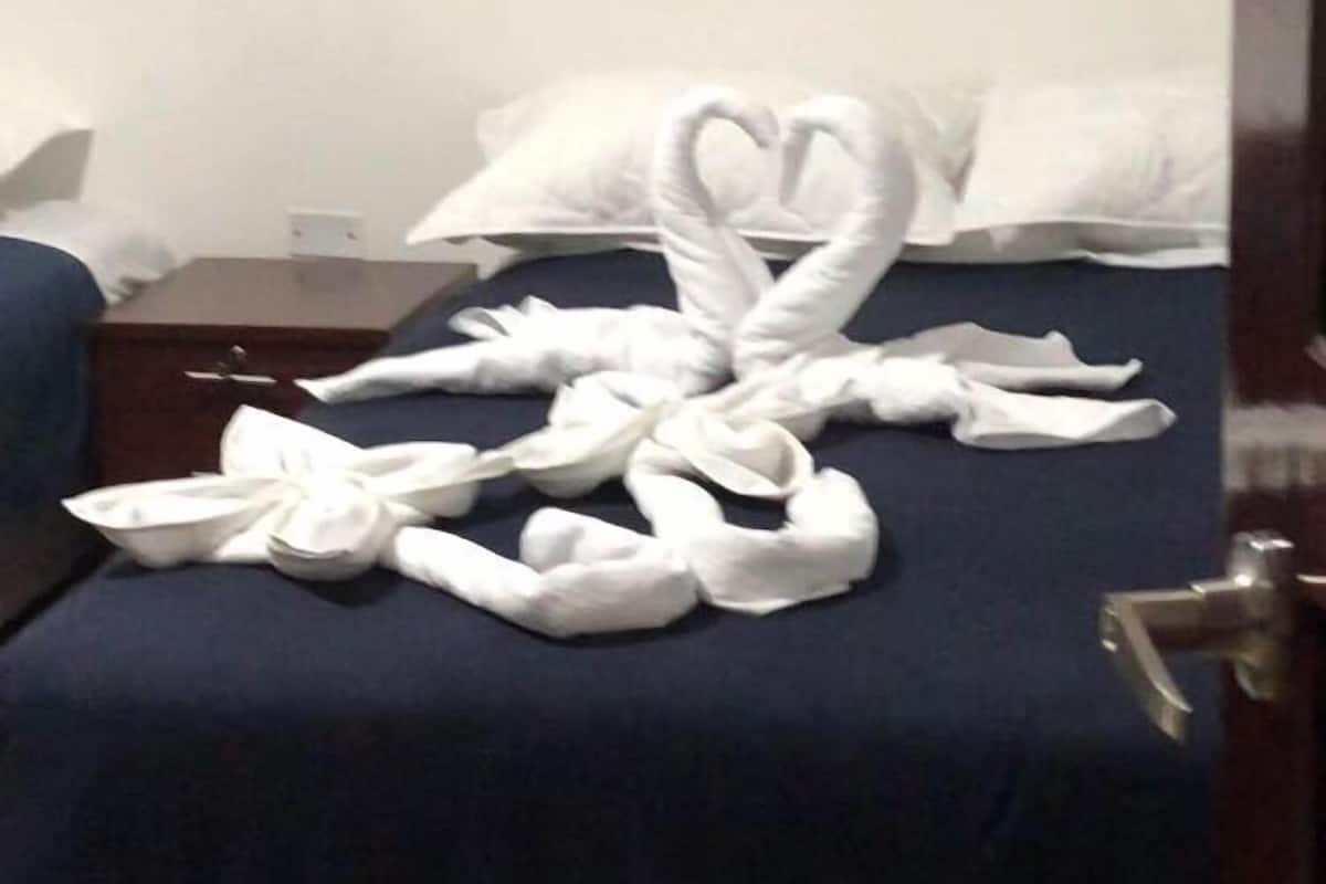 Habitación de hotel con una cama cubierta de toallas blancas dispuestas en forma de corazón.