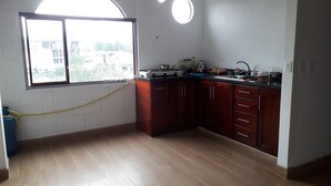 Una cocina con armarios de madera, una estufa a gas, un fregadero y una ventana con vistas a edificios.