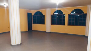 Una habitación amplia con paredes amarillas, ventanas grandes y un pilar central.