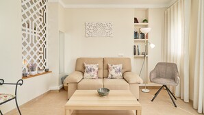 A living room with a sofa, a chair, a coffee table, a bookshelf, and a decorative wall piece. - Fernandita Apartment for Couples with 2 Private Terraces, Wi-Fi & Barbecue, Near the Beach (Nerja)