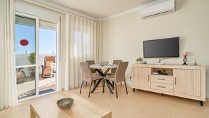 A modern living room with a dining area, a flat-screen TV, and a sliding glass door leading to an outdoor seating area. - Fernandita Apartment for Couples with 2 Private Terraces, Wi-Fi & Barbecue, Near the Beach (Nerja)