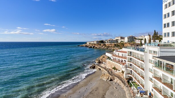 A coastal hotel with multiple balconies, a beach view, and a rocky shoreline. - Fernandita Apartment for Couples with 2 Private Terraces, Wi-Fi & Barbecue, Near the Beach (Nerja)