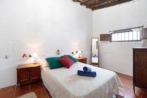 A bedroom with a bed, two bedside tables, a nightstand, a mirror, and a window.