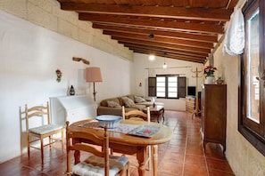 A dining area with a wooden table and chairs, a white refrigerator, a sofa, and a window with a view.